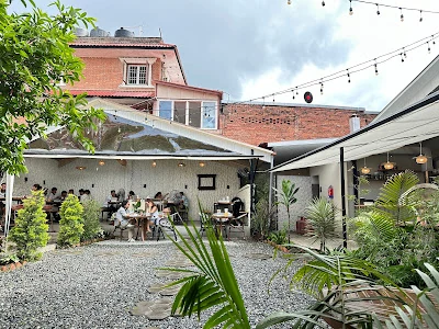 The Gardens courtyard with outdoor tables, plants and gravel paths in daylight
