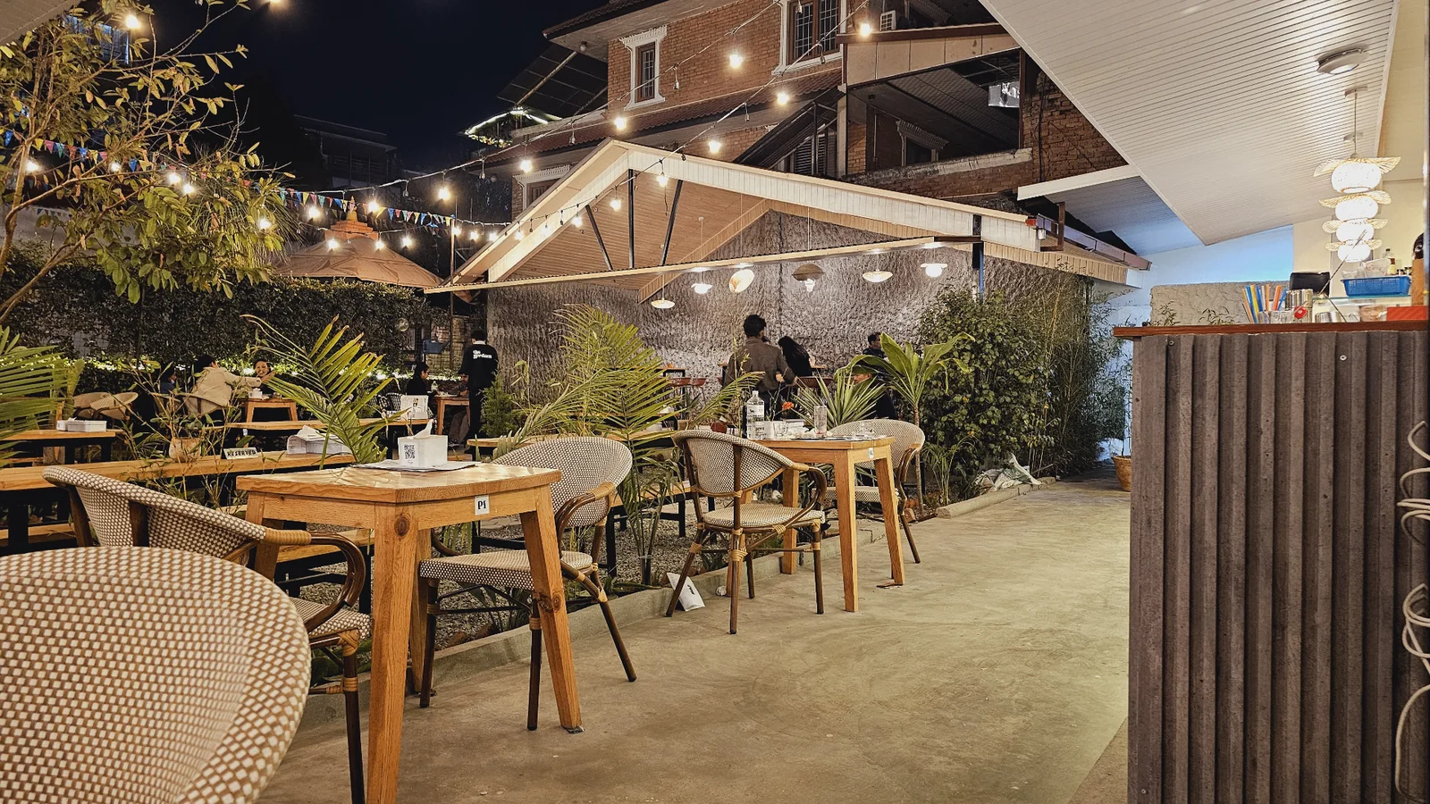 The Gardens open-air dining space glowing under evening lights